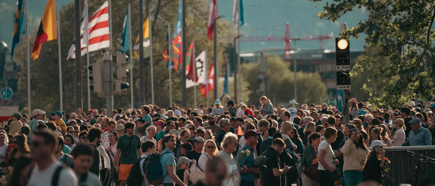 Dense crowd on a city street beneath international flags
